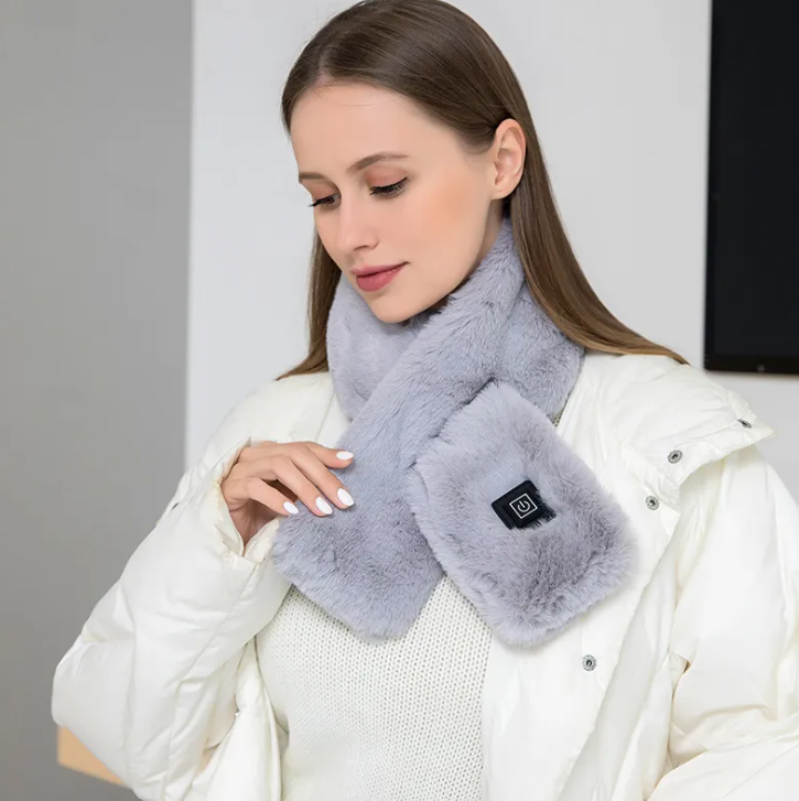 Mujer con bufanda térmica eléctrica gris puesta sobre un abrigo blanco